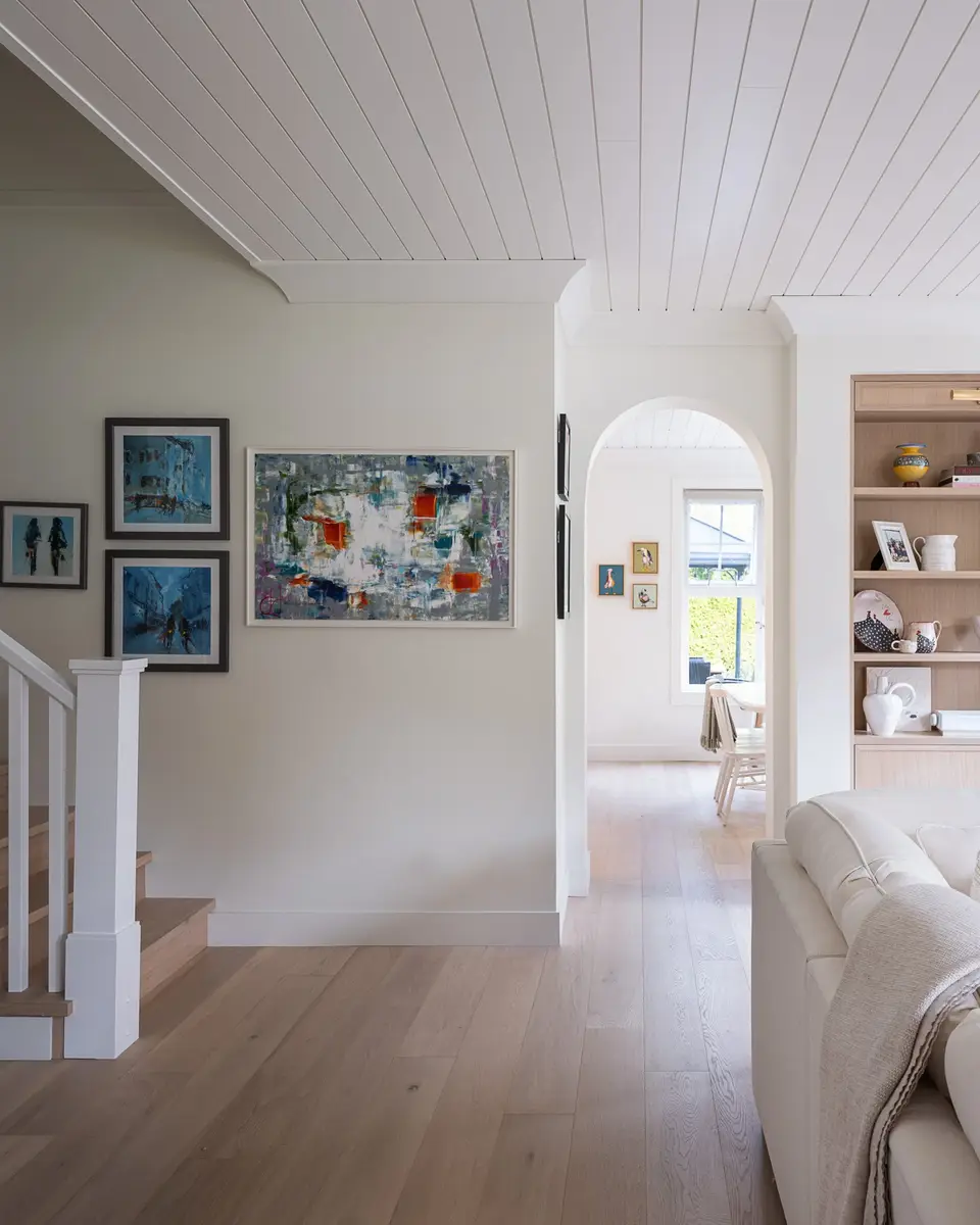 Hall past a gallery wall of framed art, an arched opening to the room beyond
