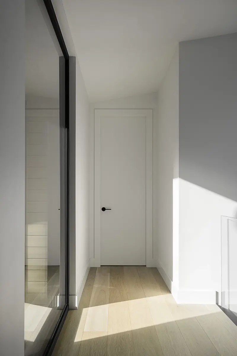 Sunlight across a pale wood floor in a hallway, a glazed partition along one side