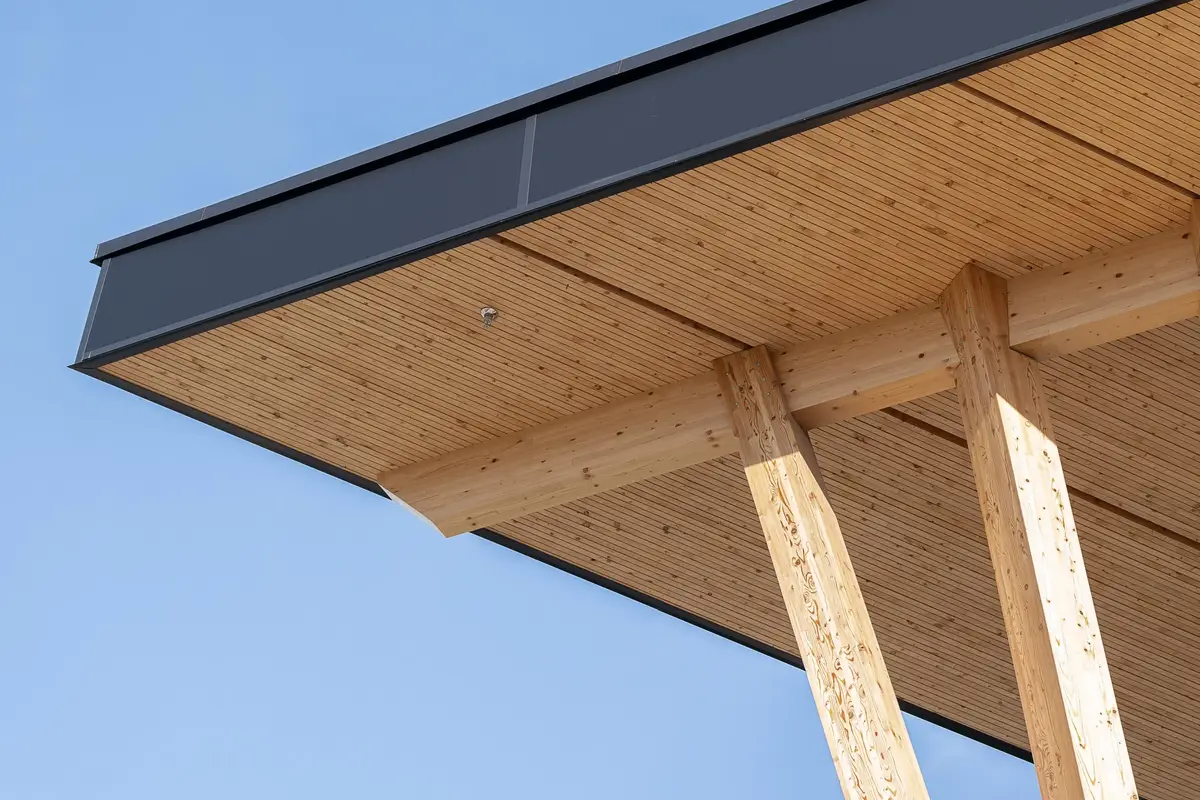 Looking up at the underside of the roof, wood soffit boards and two raking timber columns