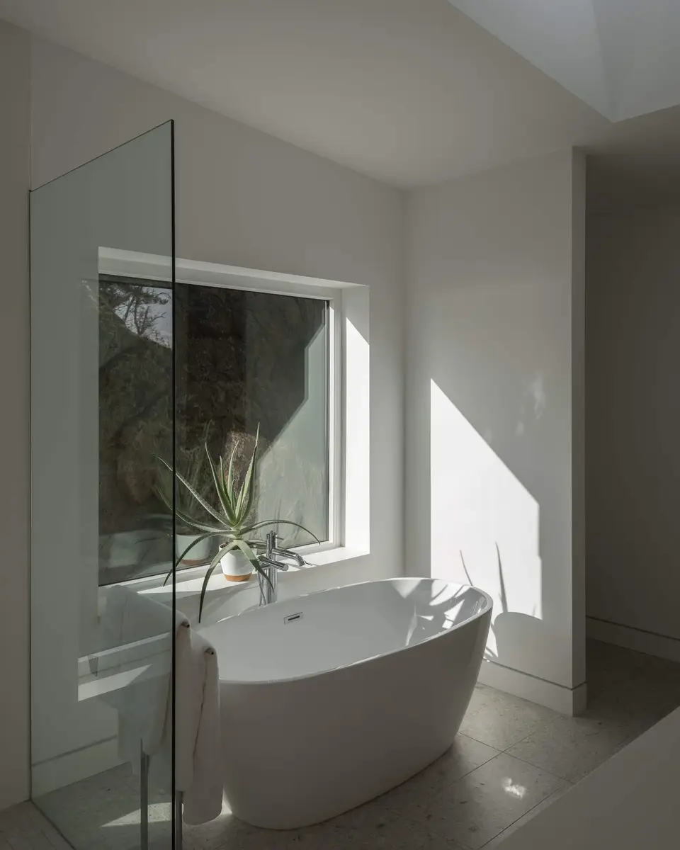 A freestanding tub at a window looking straight onto the rock face outside
