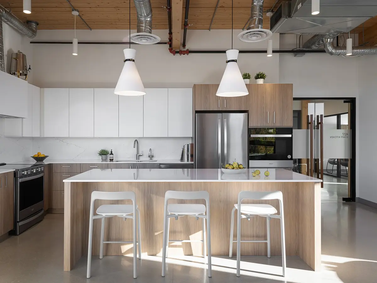 Staff kitchen with white cabinets, a wood island and stools under exposed ducts