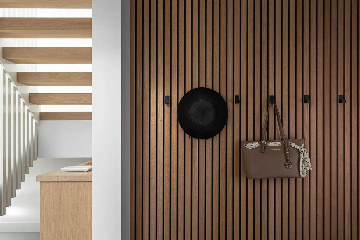 Mudroom with a slatted oak wall, coat hooks and an open riser stair beyond