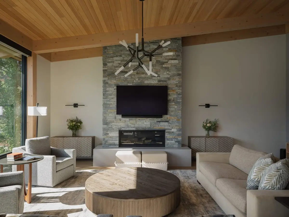 Stone fireplace between wall sconces, sofas and armchairs around a low round table