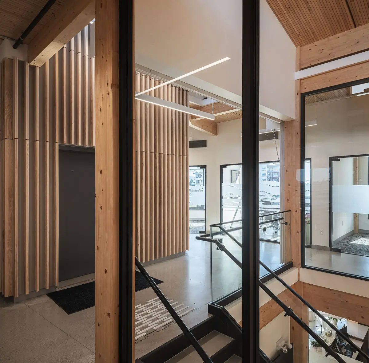 Stair and landing seen through the glazing, timber columns and a slatted wall around it