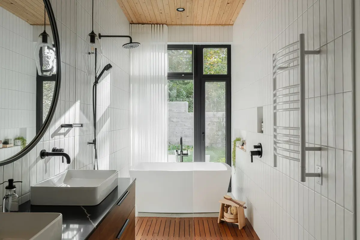 Bathroom with a freestanding tub at a full height window, twin basins on a dark counter