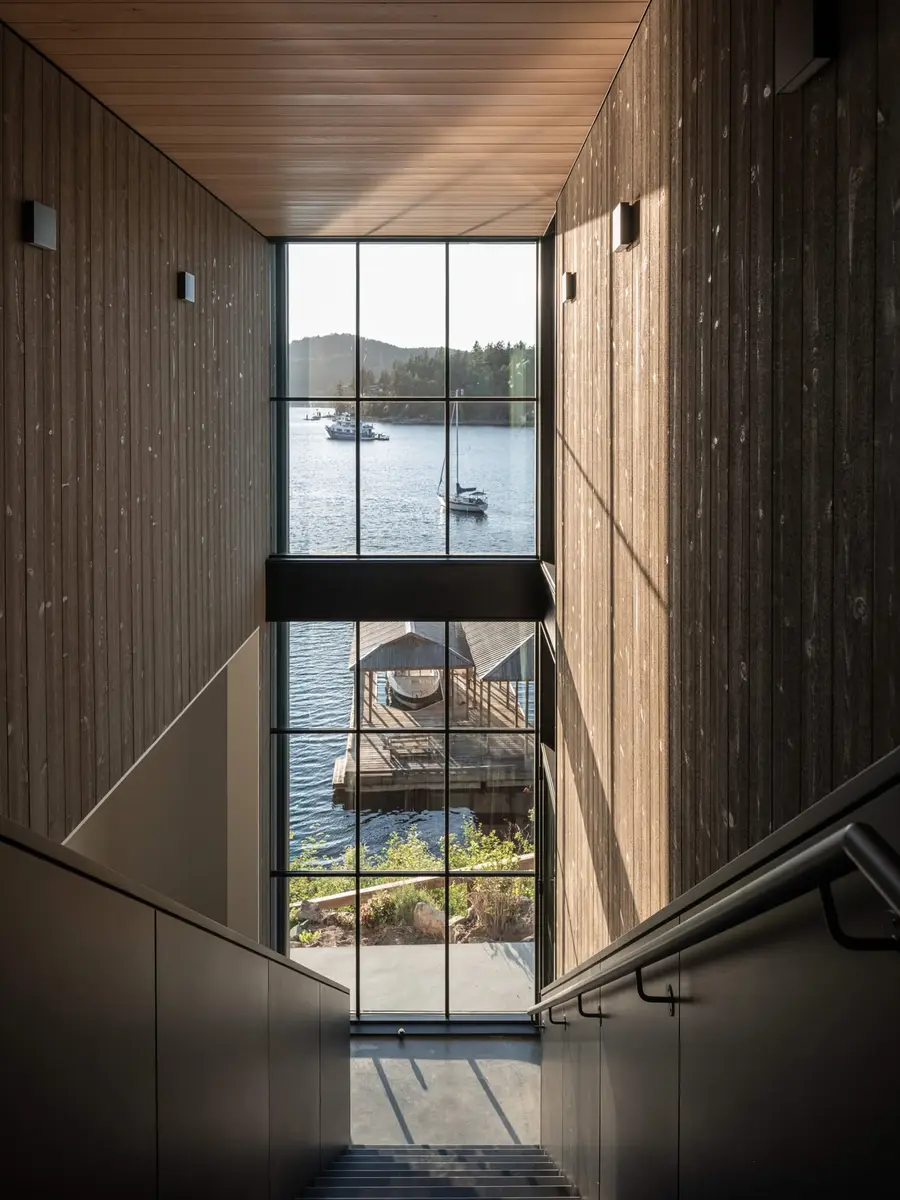 Two storey stairwell window over the bay, a moored sailboat and the boathouse below