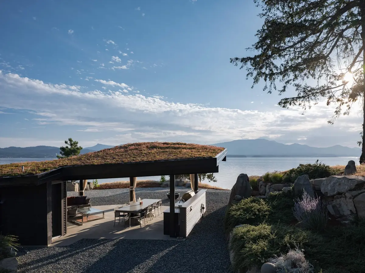 The pavilion under its planted roof above the shore, mountains across the water
