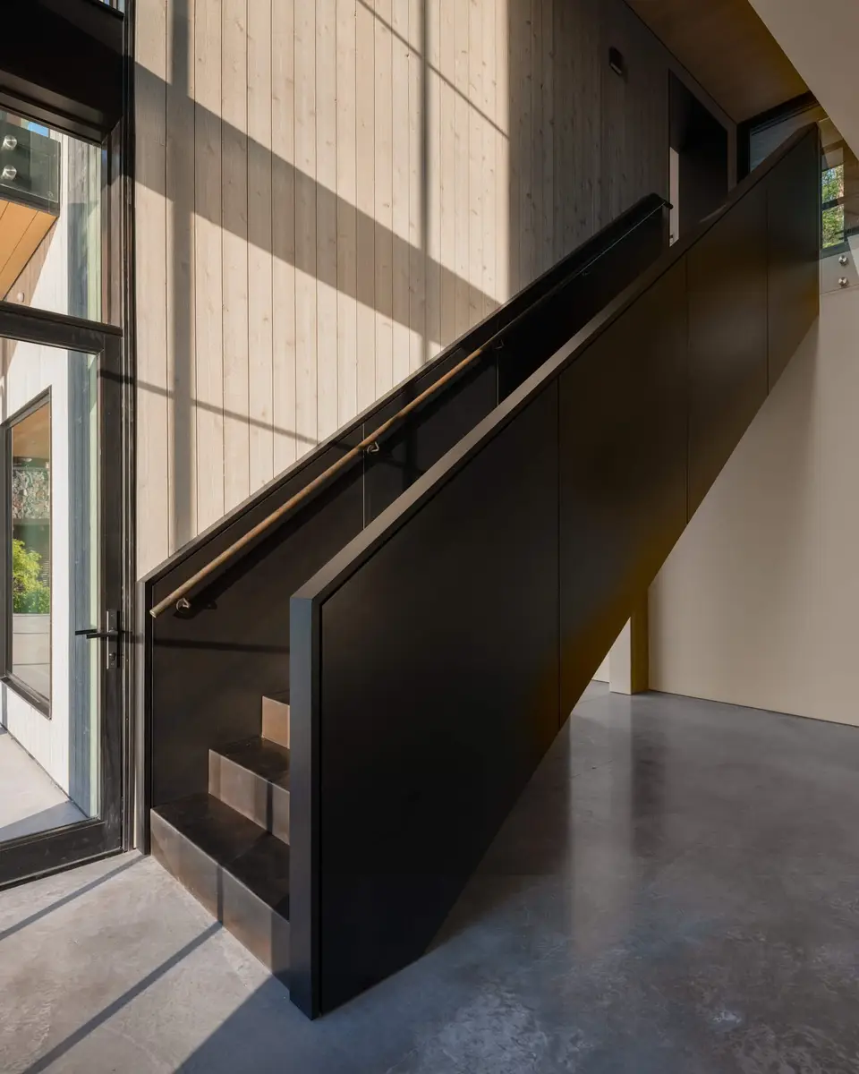 Entry hall stair with a dark steel guard and a slim brass coloured handrail
