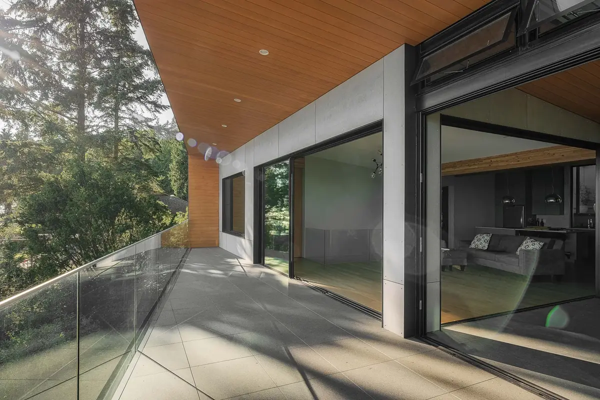 Terrace running the length of the glazing behind a glass rail, wood soffit above