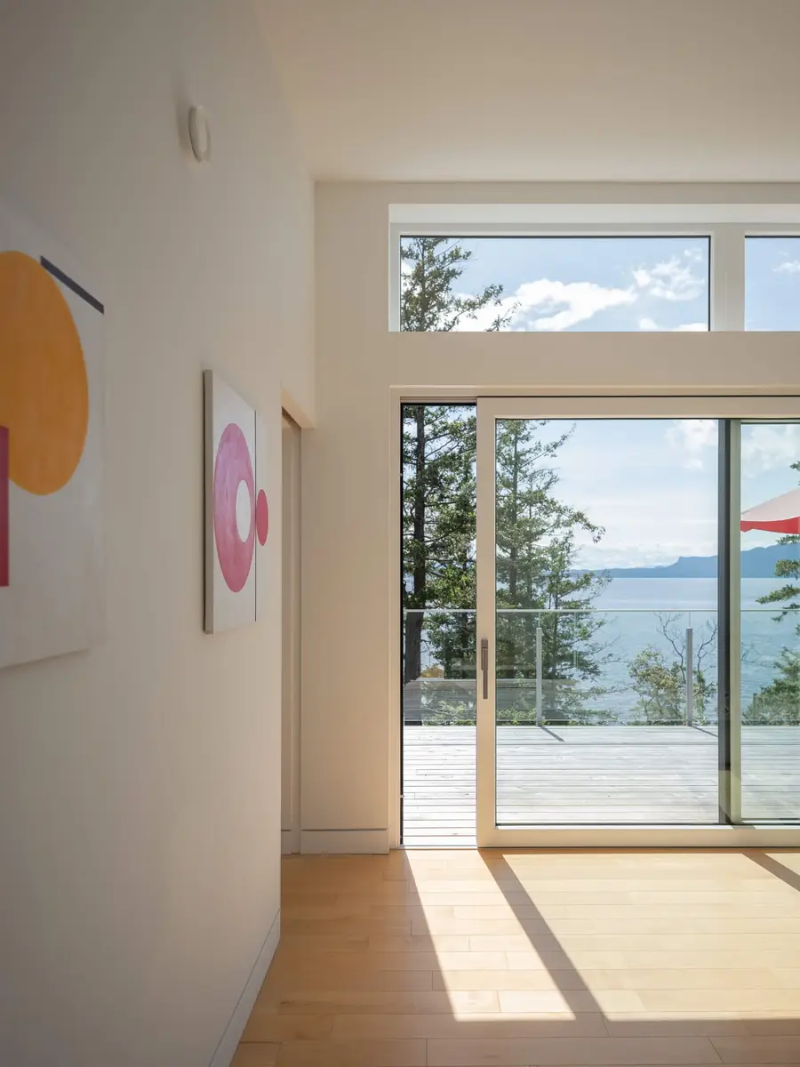 Hall lined with artwork leading to a glass door onto the deck and the water