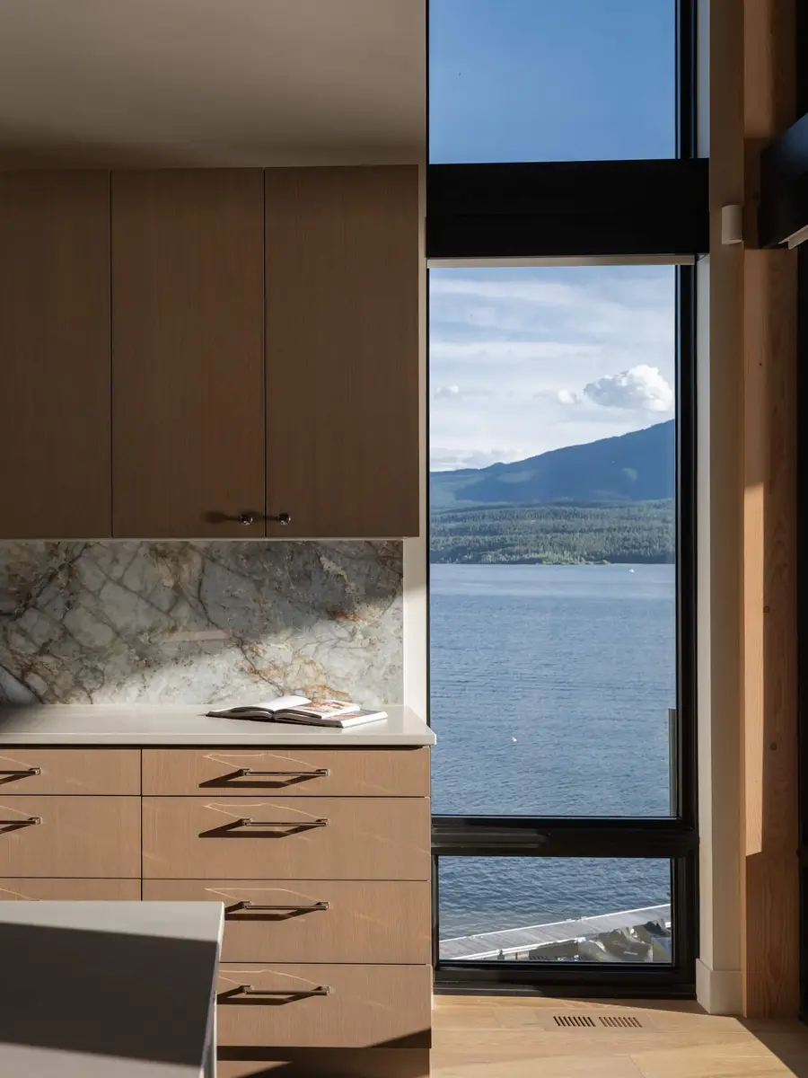 Veined stone backsplash above a run of drawers, a tall window onto the lake