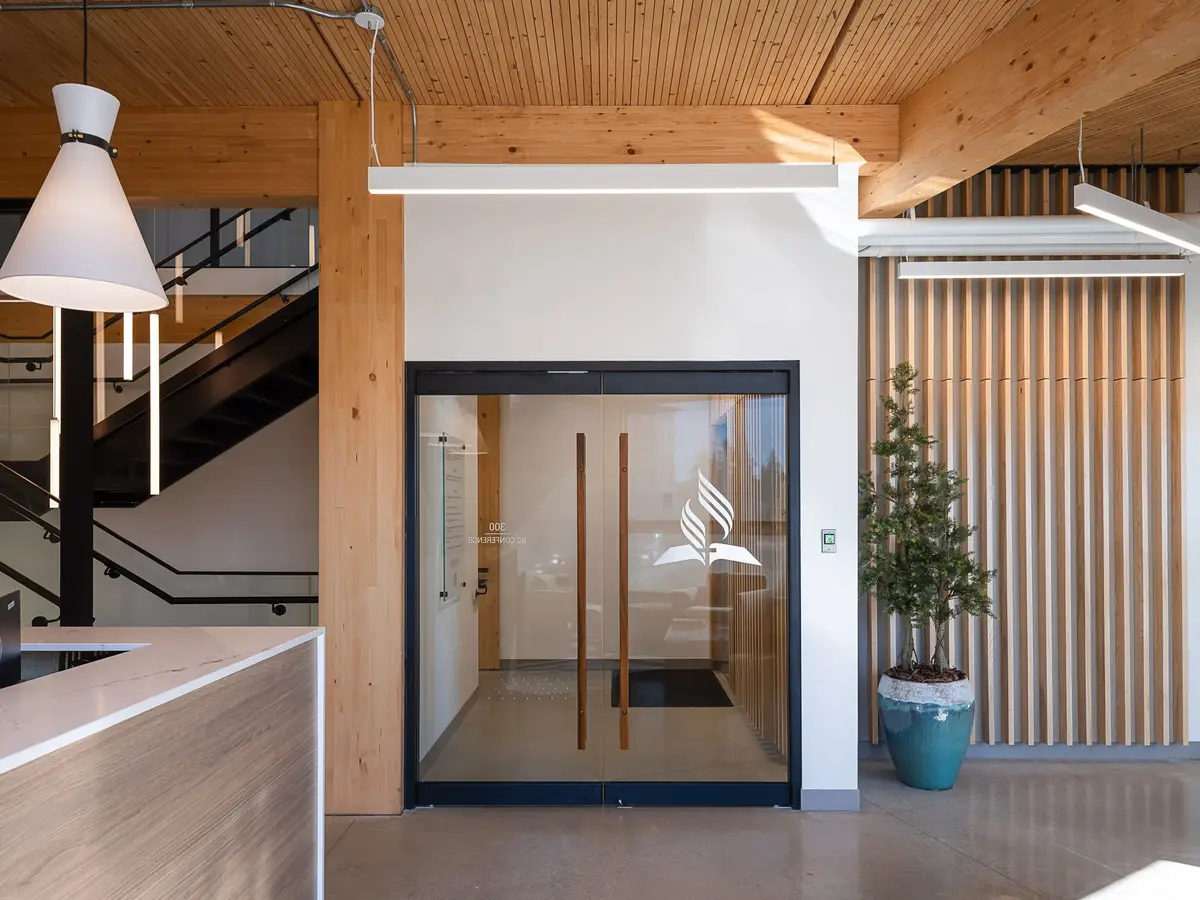 Glazed door with an emblem beside the reception counter, a stair rising behind the wood screen