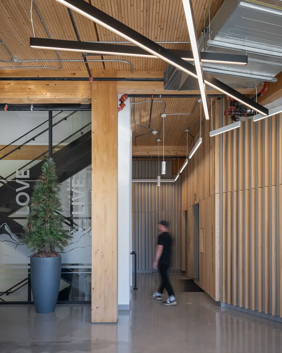 Corridor lined with wood slats, a figure walking past graphics etched on the stair glazing