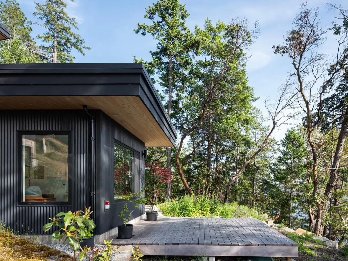 The building corner under a wood soffit, its deck carried out over the slope