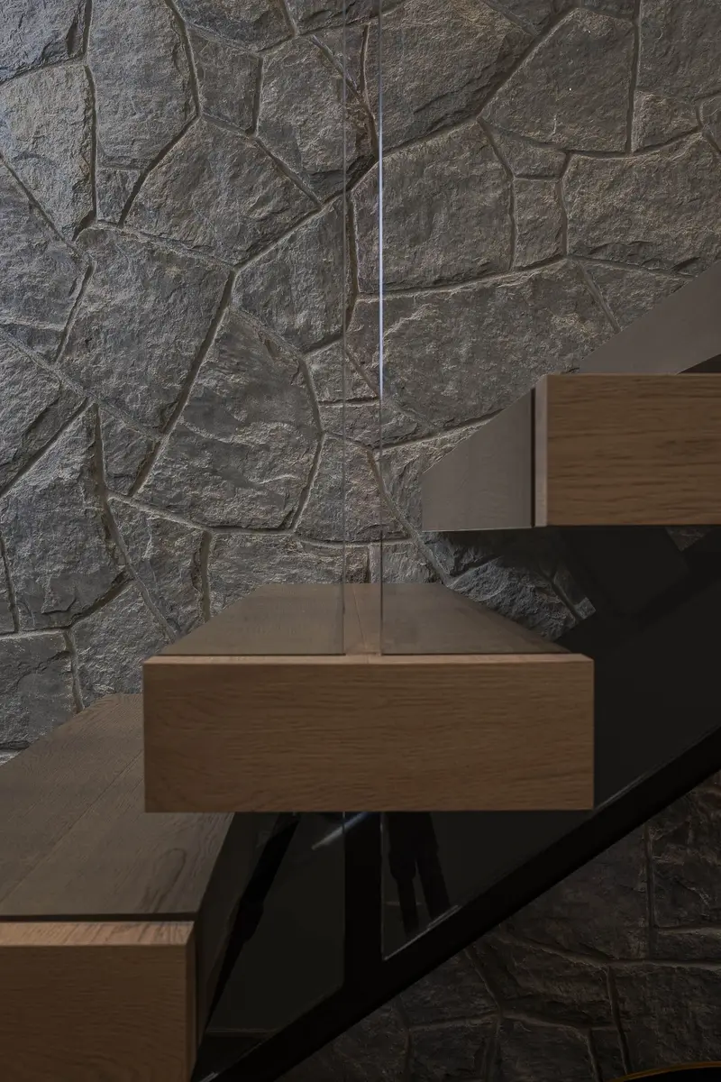 Floating treads cantilevered from a black stringer, rough stone behind