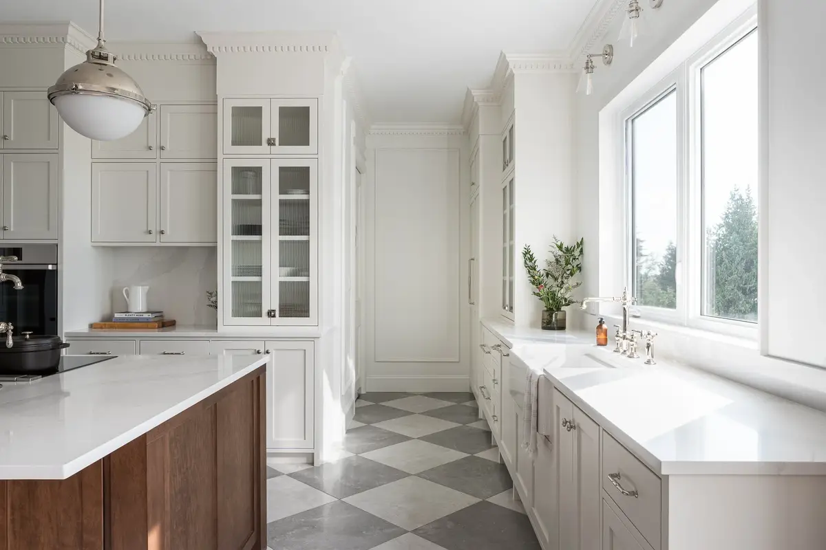 Looking down the kitchen to an apron sink set under a window onto the trees