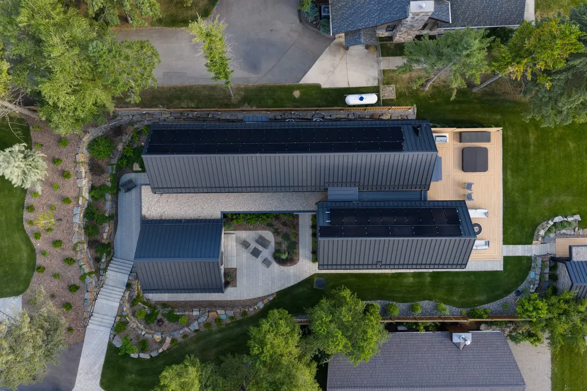 Overhead view of dark roofs carrying solar panels, courtyard and deck between the wings