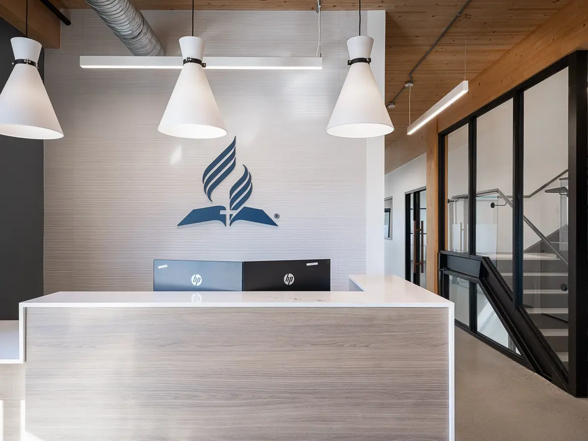 Reception desk in pale wood beneath a wall emblem, three conical pendants hanging above