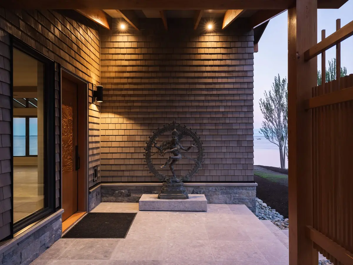 Entry court at dusk, a dancing figure on a plinth beside the lit door