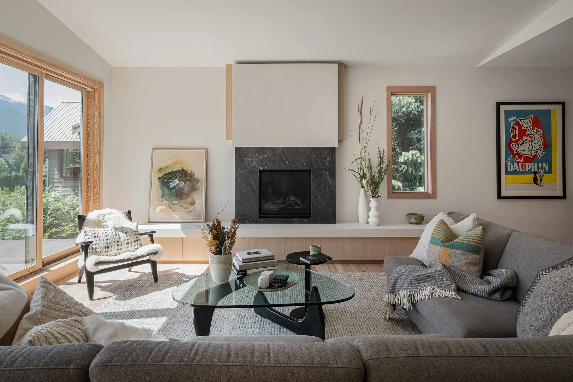 Living room with a sectional and glass table, sliding door to the deck and trees