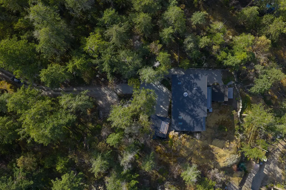 Looking down on the dark roof set into a stand of firs above the shoreline