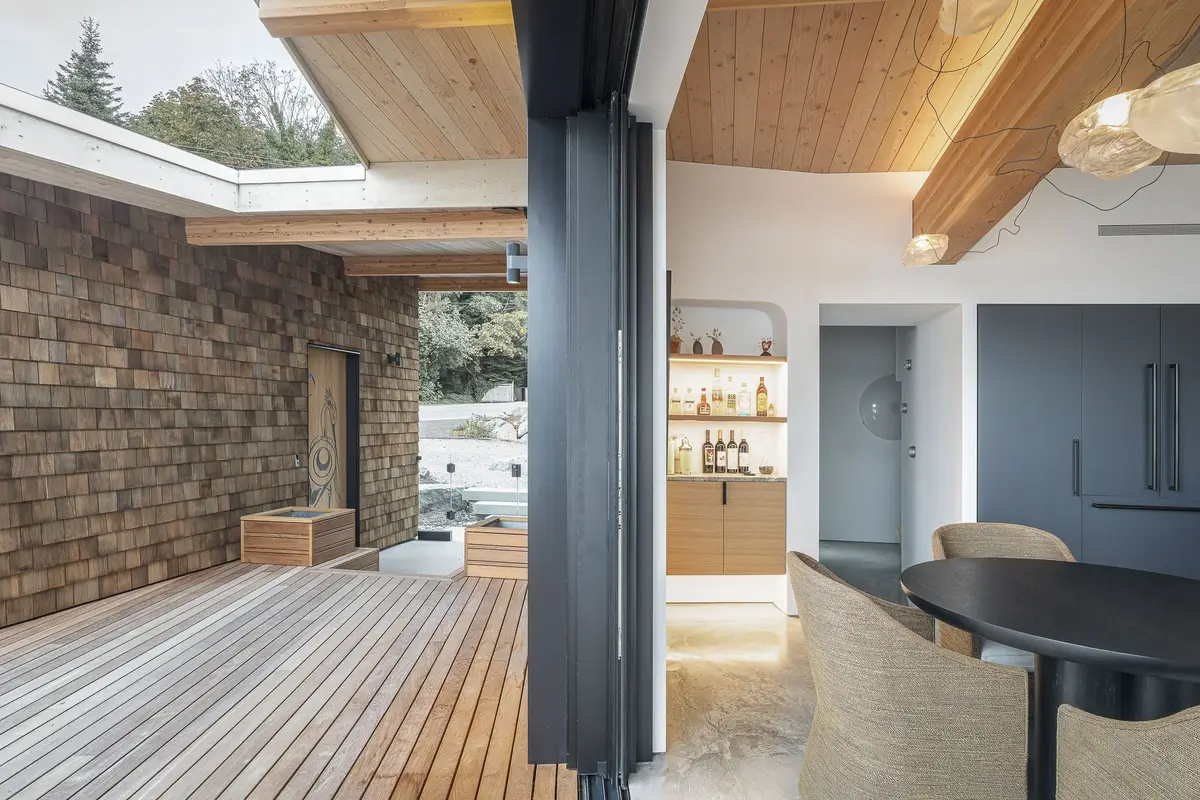Deck boards leading through an opening in a shingled wall into the dining room