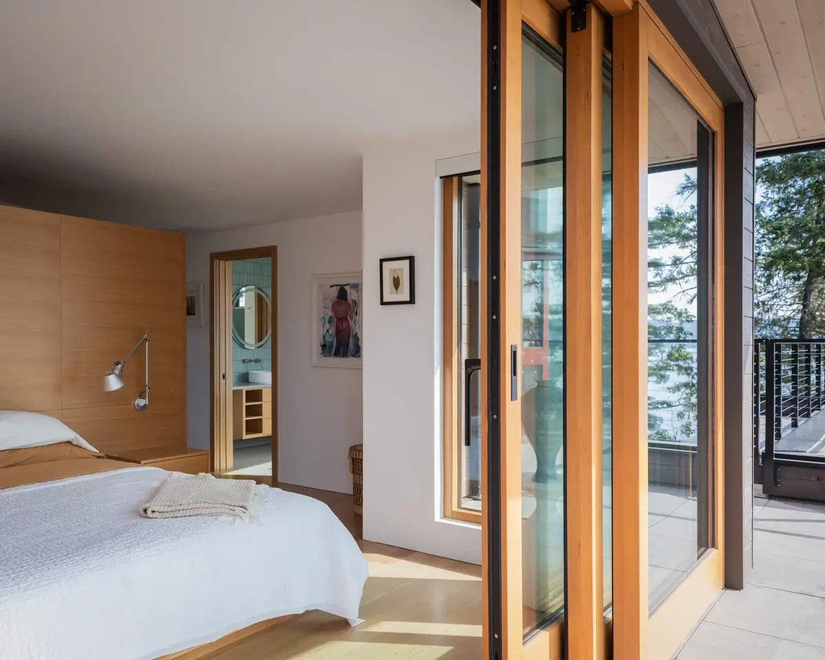 Primary bedroom with sliding doors open to a deck and the water beyond