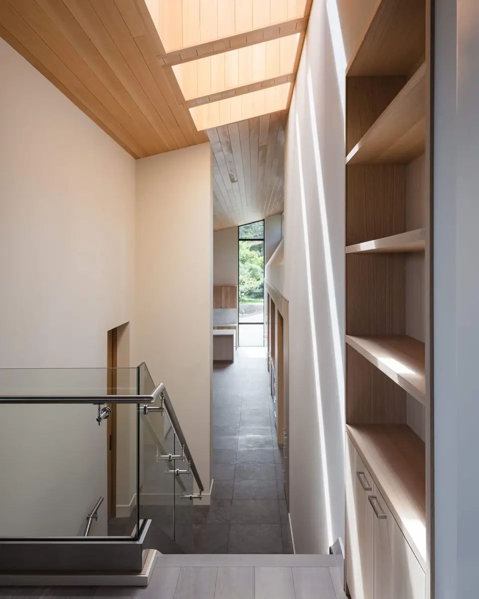 Upper hall under a run of skylights, tall shelving to one side and a glass balustrade