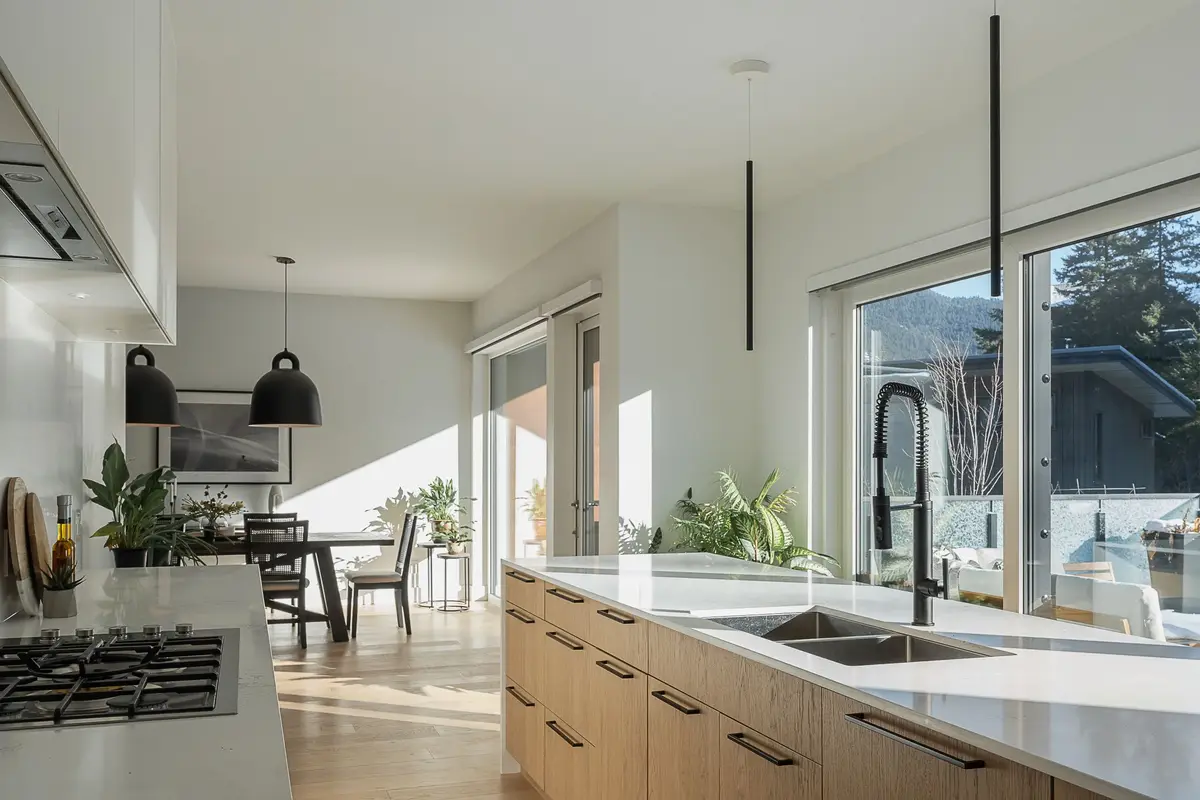 Kitchen counter in the foreground, dome pendants over the dining table and full height glazing