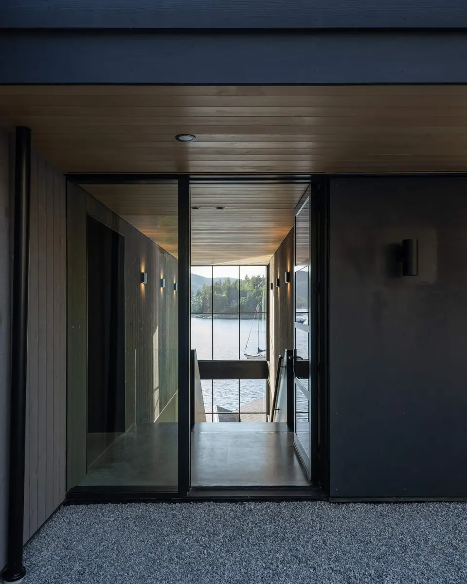 Entry at dusk, the door open on a lit hall running through to the water beyond