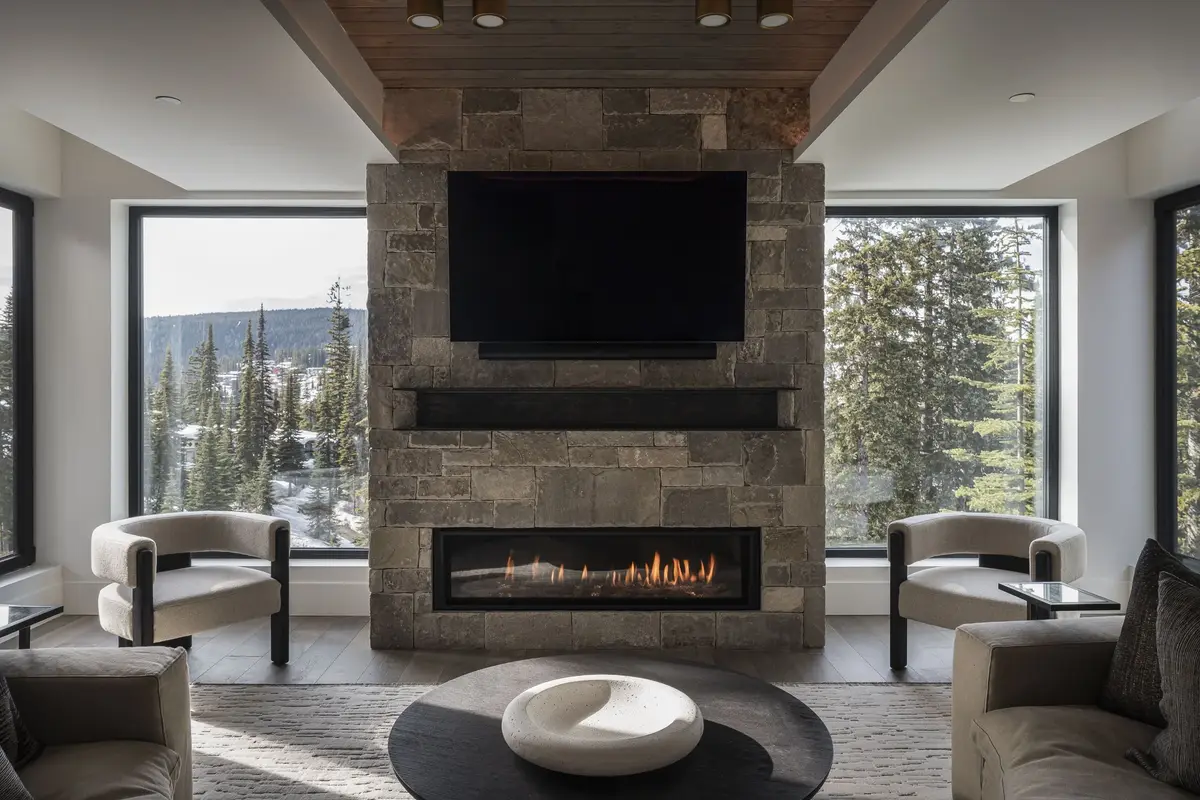Lounge with a screen above a long fireplace set in stone, two armchairs facing