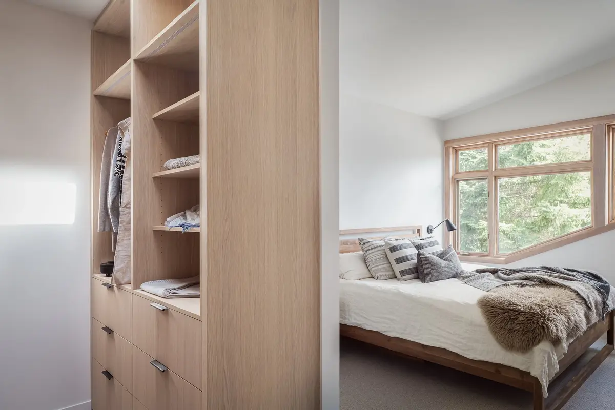 Closet joinery in the foreground opening to a bed below a corner window