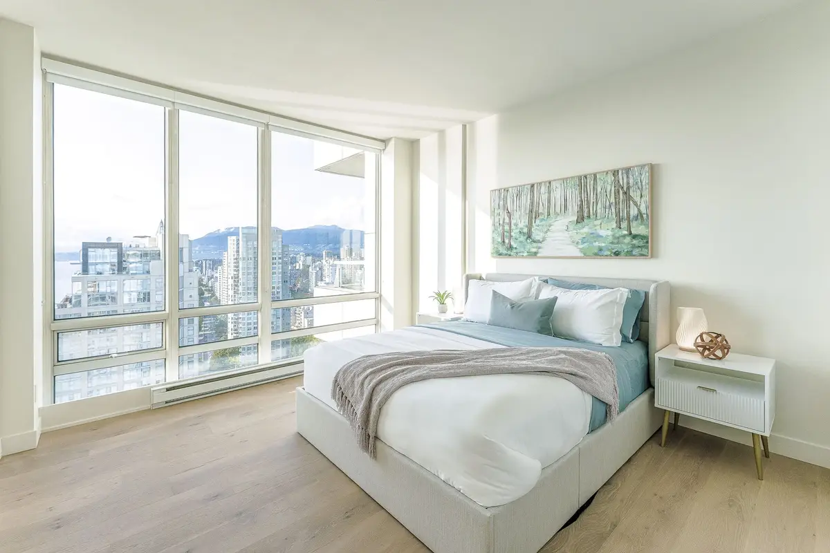 Bedroom with a landscape painting above the bed, mountains and city through the corner glass