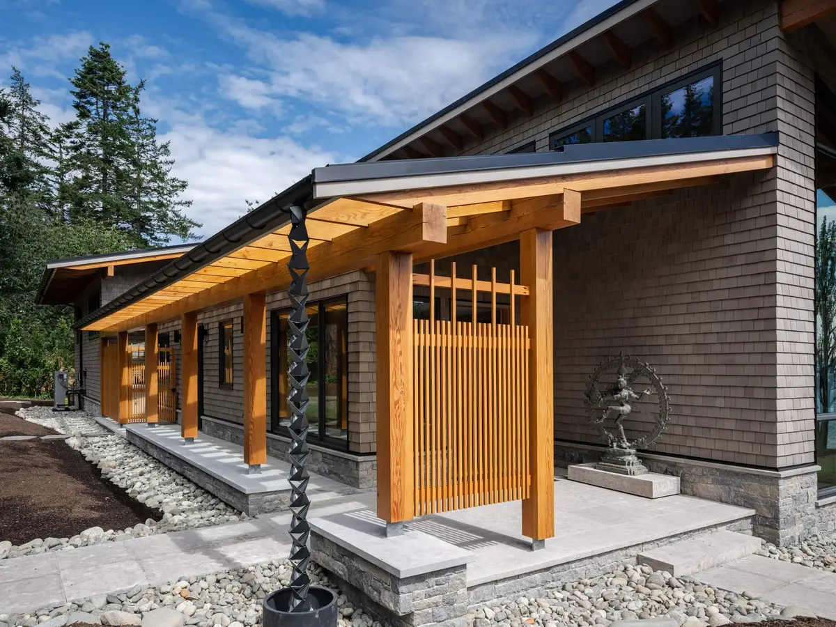 Timber posts and a slatted screen at the entry, a rain chain dropping to a basin