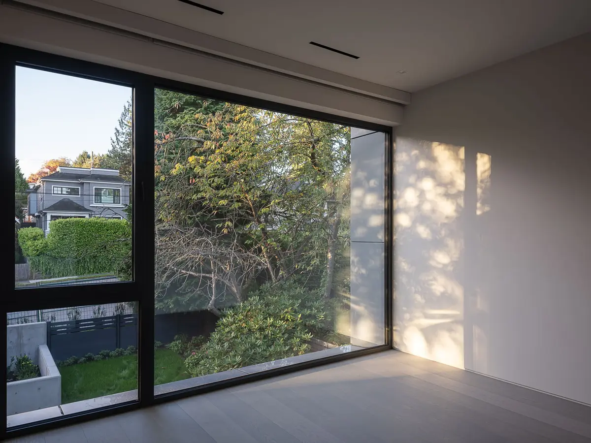 Corner glazing to the garden and hedge, dappled light across the end wall