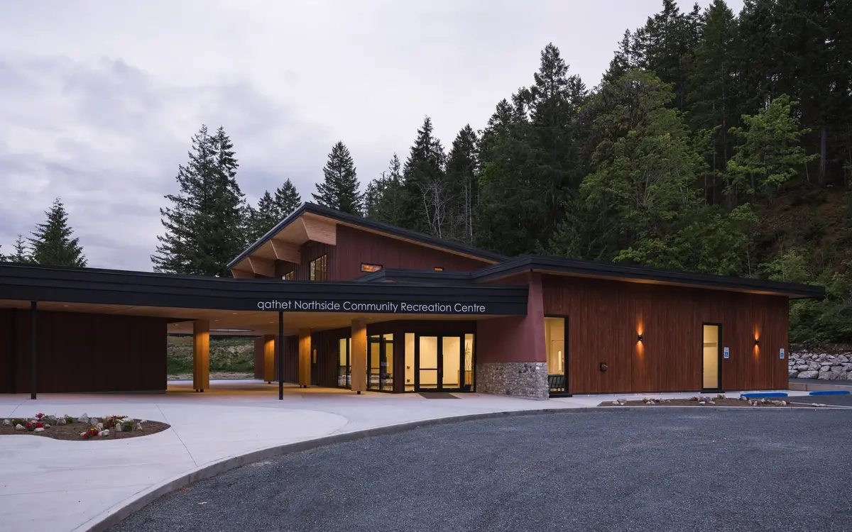 The centre at dusk, the covered walk and lobby lit behind the named fascia