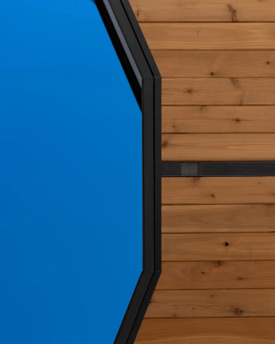 The faceted corner of the roof opening against sky, timber lining behind