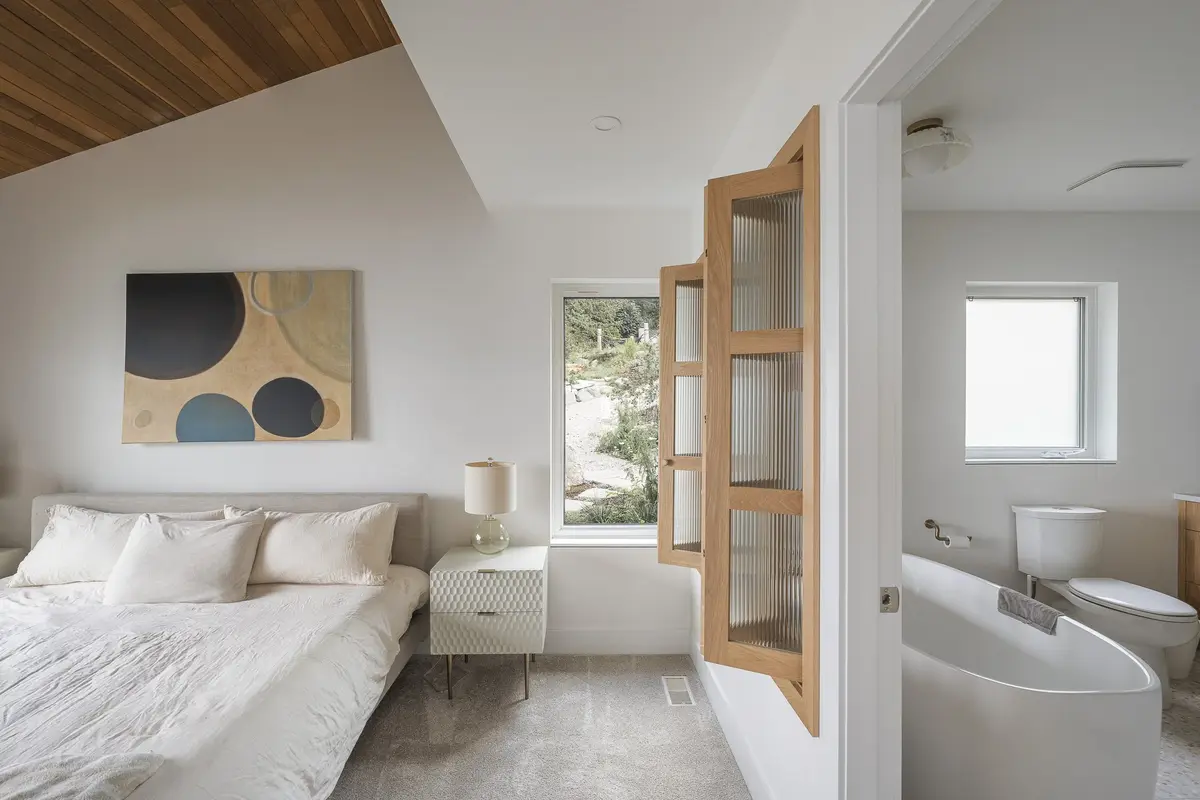 Bedroom with an abstract work above the bed, reeded glass doors open to a freestanding tub