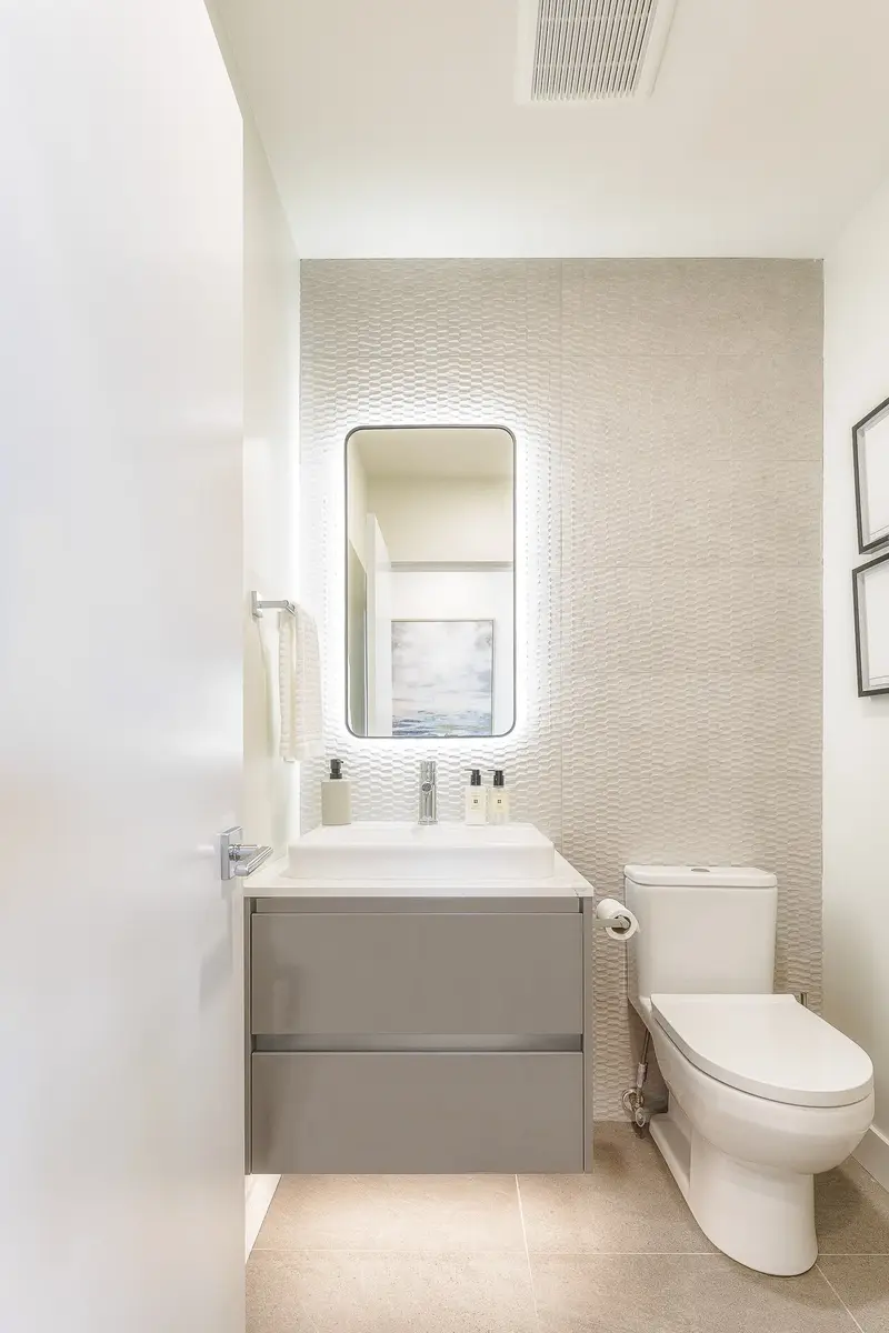 Powder room with a vessel sink on a floating vanity, textured tile behind the mirror