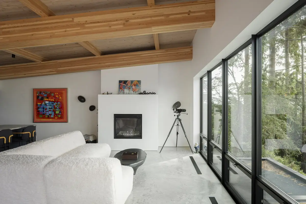 Living room under timber beams, white sofa facing a fireplace with a telescope alongside