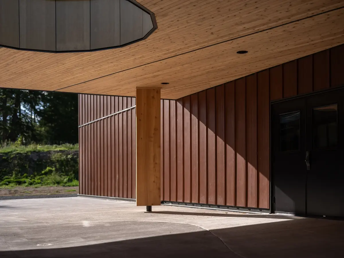 Covered walk with a timber column, vertical cladding and glazed doors to the lobby