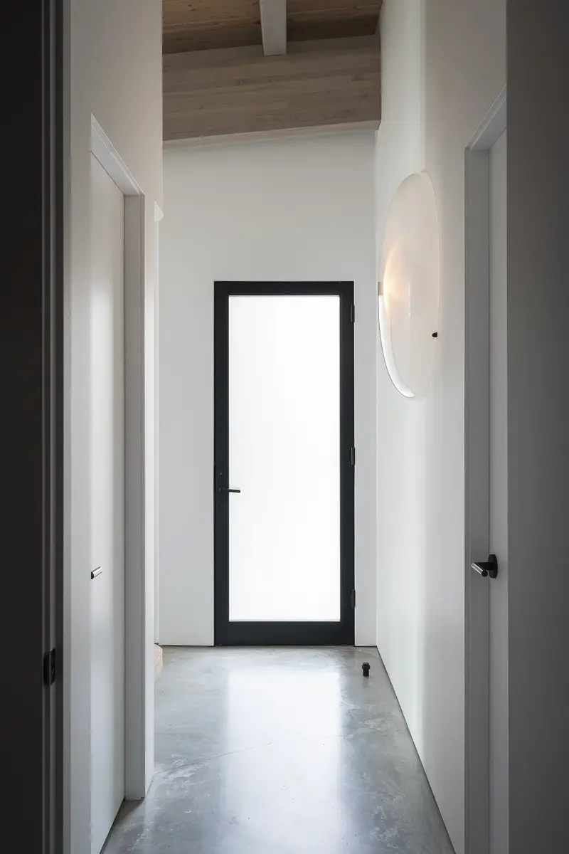 A passage ending at a frosted glass door, a round wall light alongside