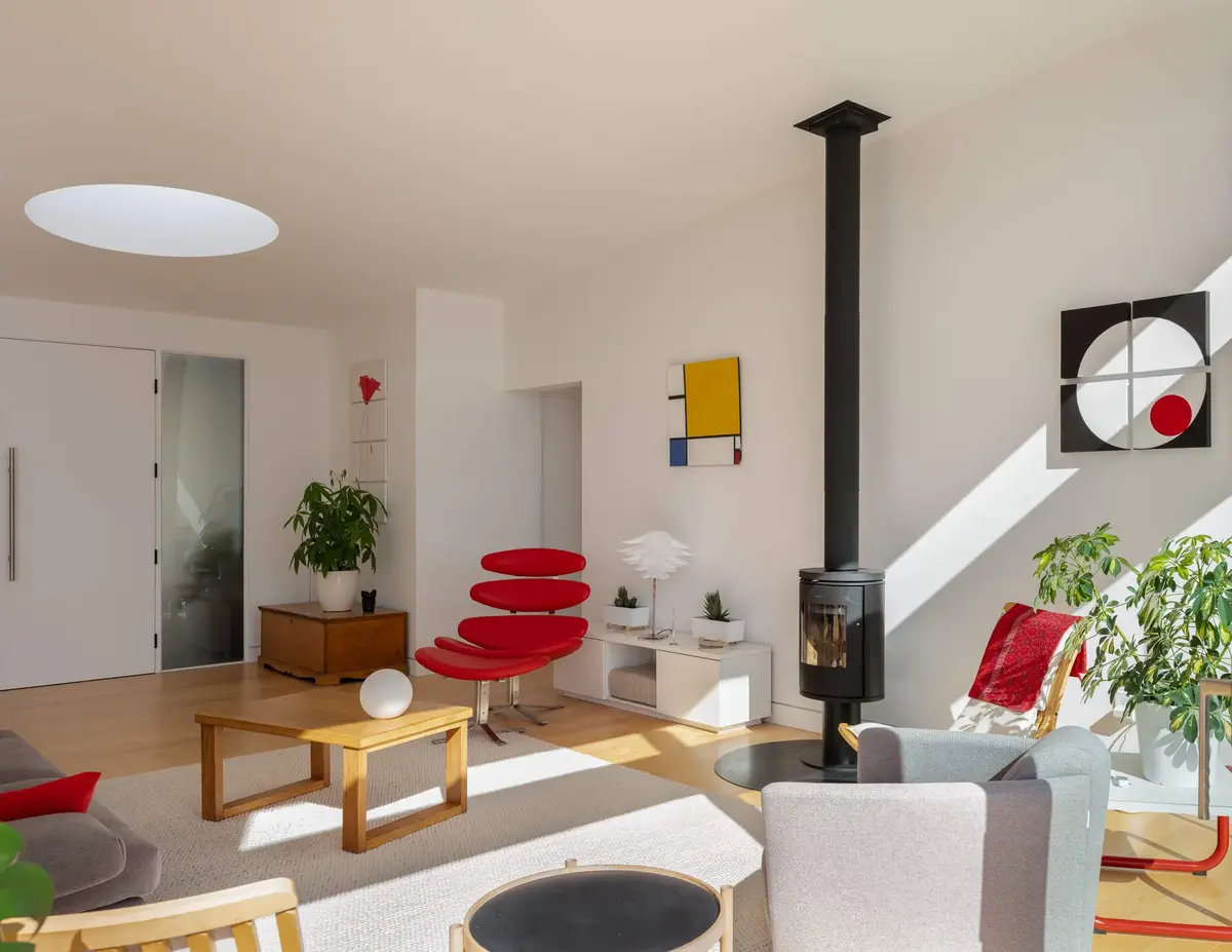 Living room seen from the entry, a wood stove and black flue against white walls