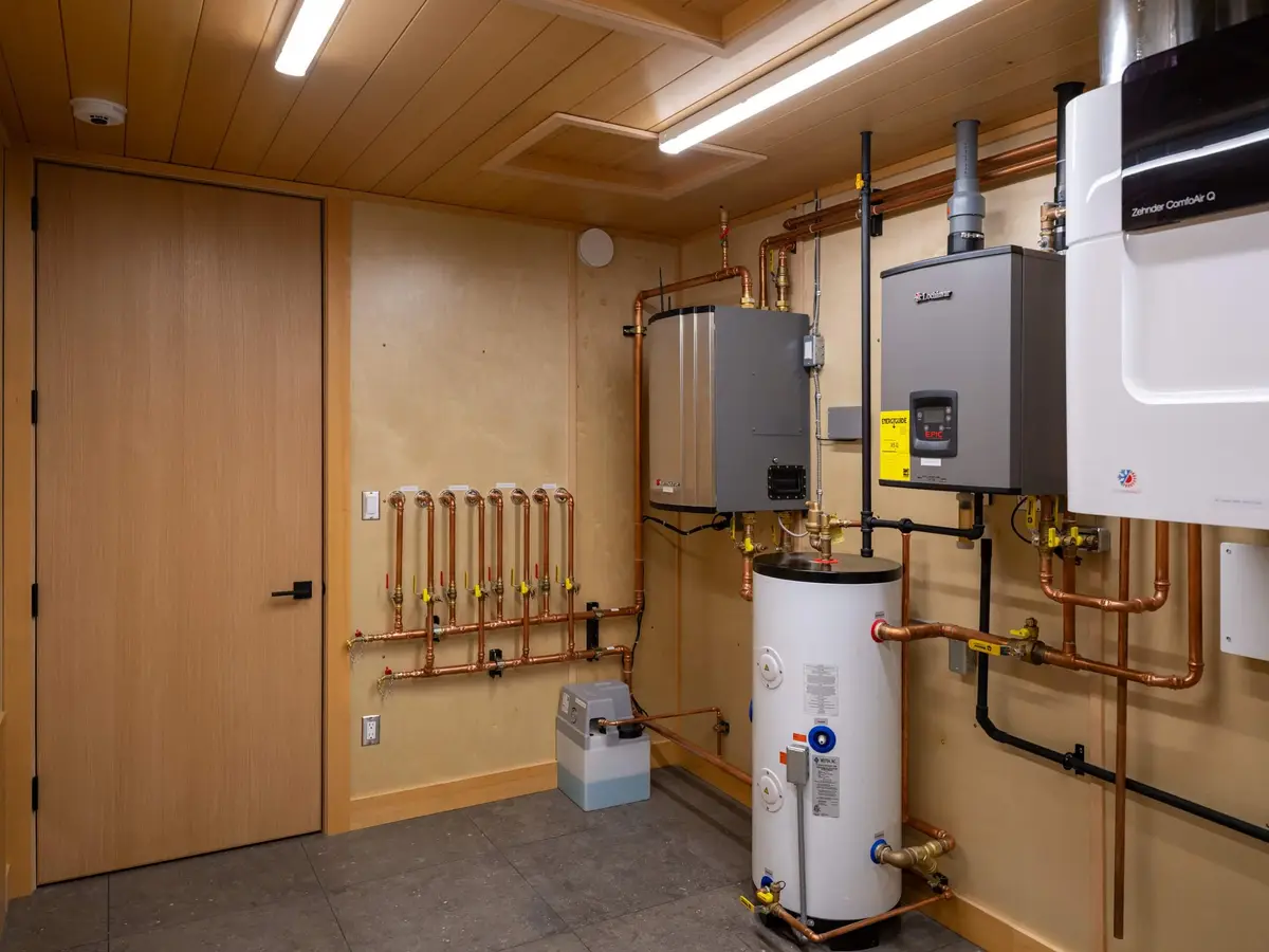 Mechanical room with wall mounted units, a floor standing tank and runs of copper pipe