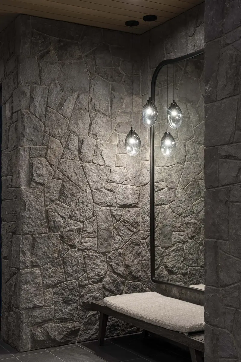 Bench in a stone lined alcove beneath a wall light with three glass globes