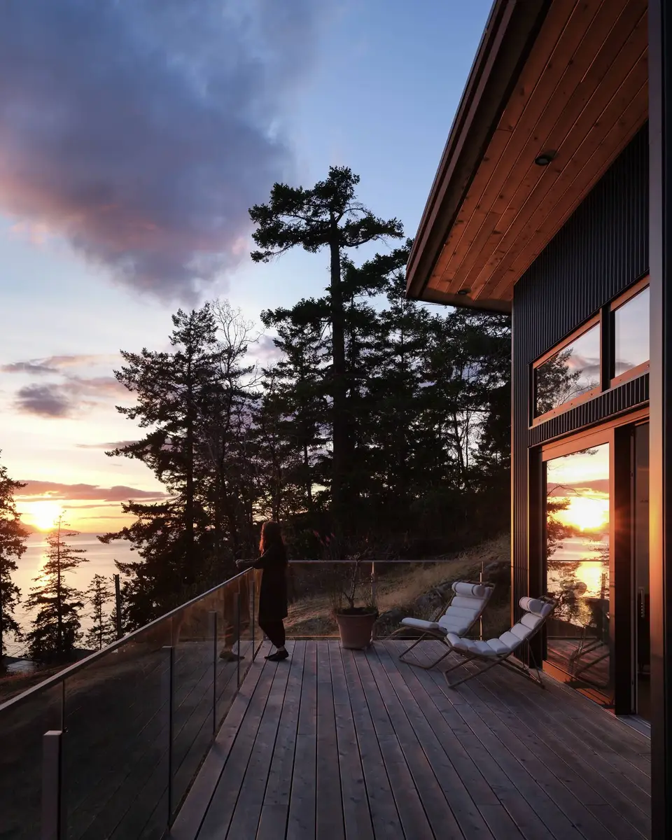Sunset from the deck, a figure at the glass rail and loungers under the soffit