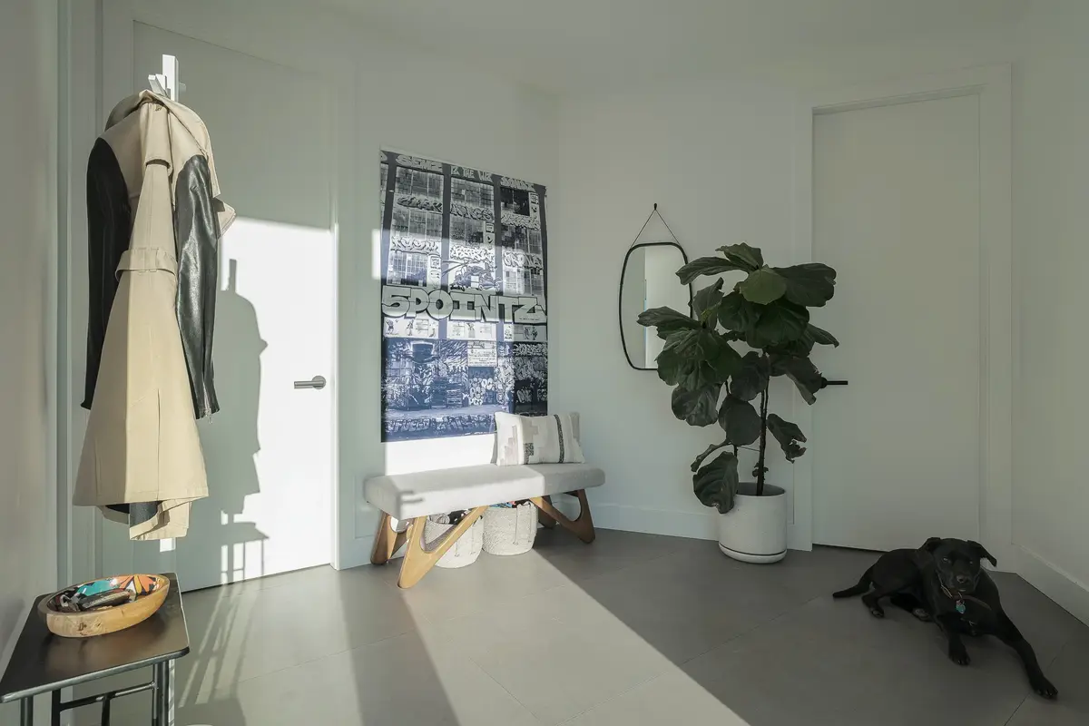 Entry room with a coat stand, an upholstered bench and a black dog resting on the tiled floor