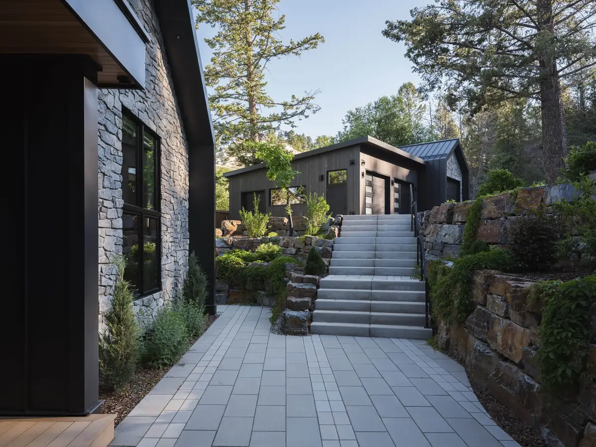Paved path beside a stone wall, steps climbing between boulder retaining walls