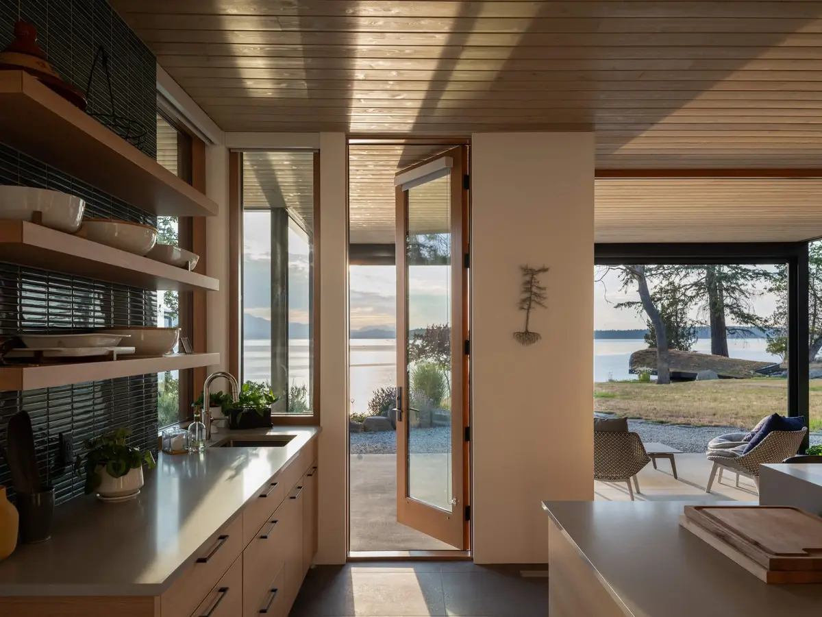 Prep counter with open shelves beside a door standing open to the water