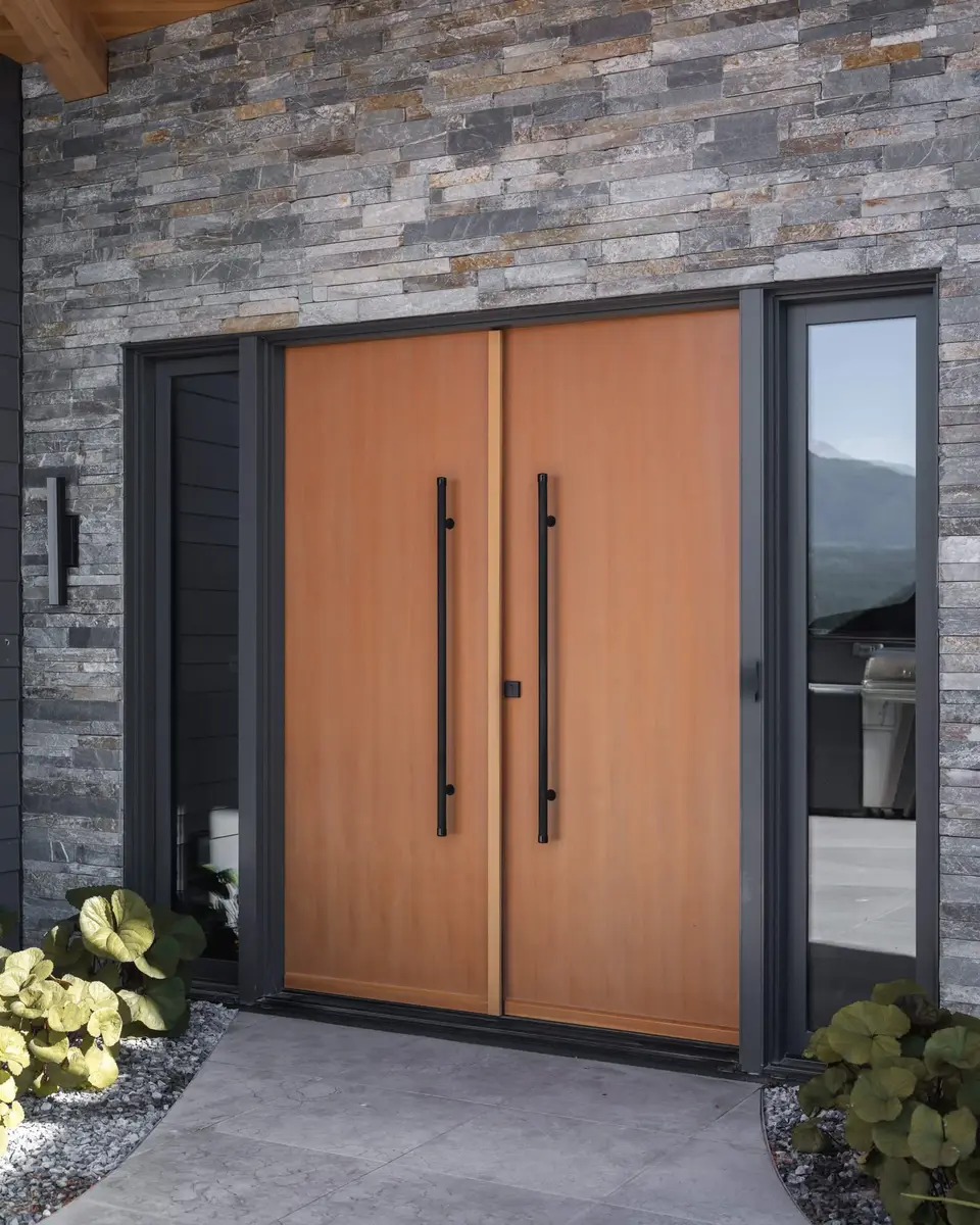 Wood double doors with long black pulls set into a stone wall